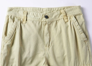 Detail of khaki cargo pants waist showing metal button closure and belt loops