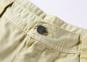 Macro shot of light khaki cargo pants waist with metal button and twill fabric texture