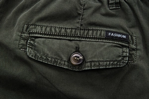 Close-up of military green cargo pants pocket with button flap and fashion woven label