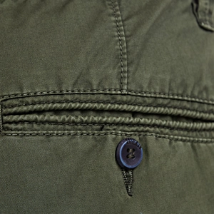 Macro shot of cargo shorts detail showing army green fabric, reinforced stitching and button