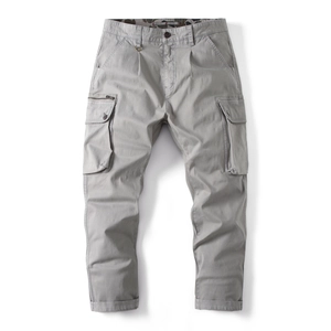 Detail of grey cargo pants showing functional flap pockets and metal zipper pocket