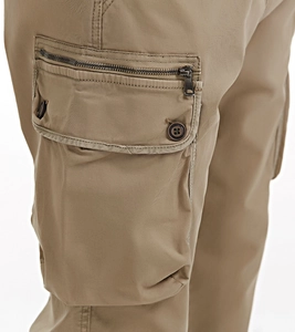 Detailed macro view of khaki cargo pants featuring functional flap pockets and metal zipper