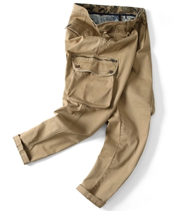 Detail of khaki cargo pants featuring large side flap pockets with metal zipper accents