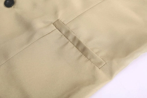 Detail view of khaki twill fabric vest featuring a flat welt pocket and black button