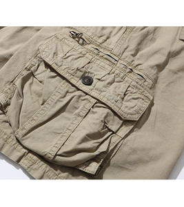 Detail of khaki cargo shorts showing the flap pocket with button and metal zipper detail
