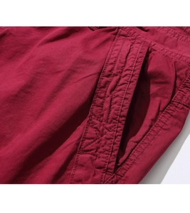 Detailed close-up of heavy-duty double stitching and reinforced pocket on wine red cargo shorts
