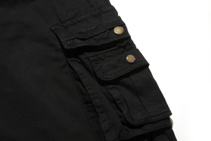Detailed view of black cargo shorts with double flap pockets and vintage copper buttons