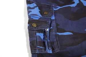 Detail of blue camouflage cargo pants showing side utility pockets and metal buttons