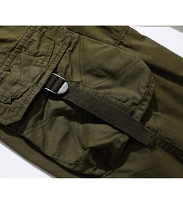 Detailed close-up of army green cargo shorts featuring metal buckle and utility pocket