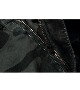 Detailed close-up of dark camouflage fabric with premium black metal zipper and precise stitching