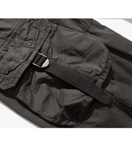 Detail of dark grey cargo shorts featuring a pocket with cross stitching and a metal D-ring