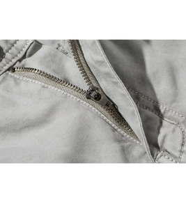 Detailed macro view of smooth metal zipper and reinforced stitching on gray shorts