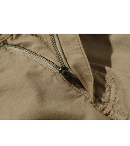 Detailed macro view of heavy-duty metal zipper on khaki cargo shorts with reinforced stitching