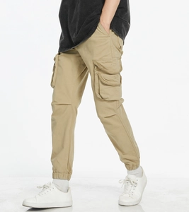 Detail of khaki cargo joggers showing the side flap pocket and elastic cuffs with sneakers