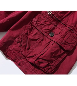 Detail of dark red cargo shorts showing durable fabric, flap pocket, and metal zipper