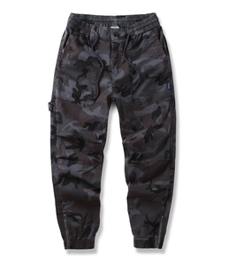 Detail of dark camouflage cargo pants with elastic waistband and ankle zipper closures