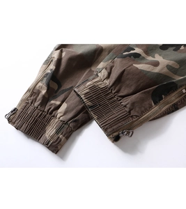 Detail of camouflage cargo pants featuring ribbed elastic cuffs and side metal zipper
