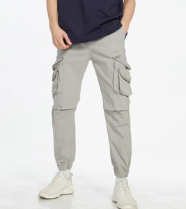 Detail of light grey cargo pants with multiple utility pockets and elastic cuffs
