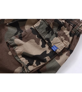 Detail of cargo pants with camouflage pattern featuring a large flap pocket and drawstring