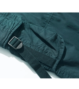 Detailed macro view of dark teal cargo shorts featuring a flap pocket and black metal buckle