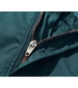 Macro view of a bronze metal zipper on dark green cargo shorts twill fabric