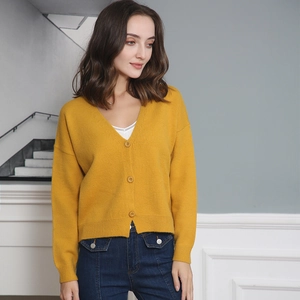 Detail of yellow V-neck knit cardigan with textured fabric and wooden-style buttons