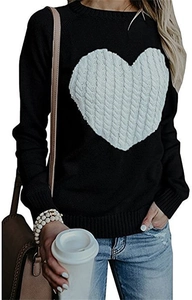 Detail of a black knit sweater featuring a white cable-knit heart patch and ribbed trims