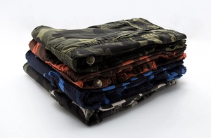 Detail of folded camo cargo shorts in green, brown, blue and grey with reinforced seams
