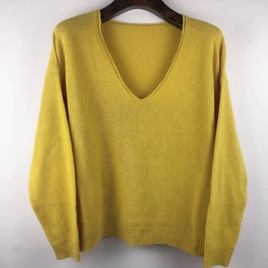 Detail view of bright yellow V-neck knit sweater featuring soft fine texture on wooden hanger