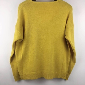 Detail view of the back of a mustard yellow long sleeve knit sweater with ribbed cuffs