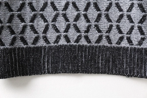 Close-up of geometric diamond knit pattern and black ribbed cuff on men's sweater