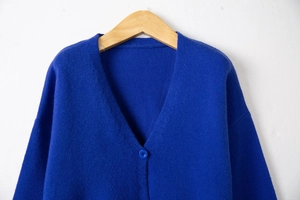 Detailed view of deep V-neckline and knit texture on bright blue cardigan with matching button