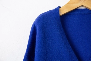 Detail shot of navy blue knit cardigan fabric showing soft texture on a wooden hanger