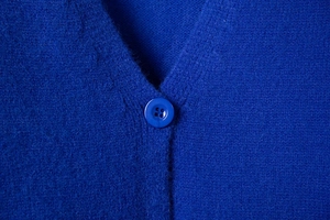 Detail of royal blue knit cardigan showing V-neckline and matching four-hole button