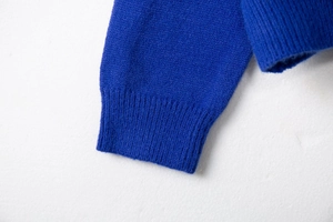 Detailed close-up of ribbed cuffs on a vibrant Klein Blue knit cardigan sweater for women