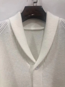 Detailed view of white ribbed knit cardigan featuring a classic shawl collar and button
