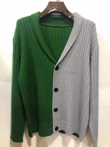 Detail of two-tone green and grey ribbed knit texture and black button closure on cardigan