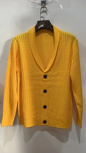 Detail of ginger yellow men's knit cardigan showing textured waffle weave and black buttons