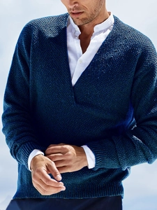Detail of dark blue V-neck knit sweater showing waffle texture and ribbed cuffs for men