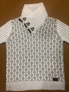 Close-up of grey knit sweater featuring diamond patterns and three dark toggle buttons