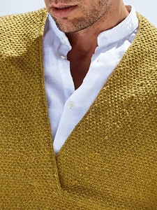 Close-up of mustard knit V-neck sweater layered with a white stand collar linen shirt