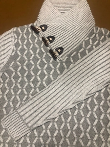 Detailed view of shawl collar with three wooden toggle buttons on a grey knit sweater