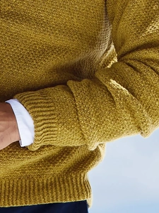 Detailed close-up of textured ginger knit sweater with ribbed cuffs and collared shirt