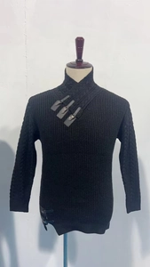 Detail shot of black knitted sweater featuring leather buckle straps and asymmetric hemline