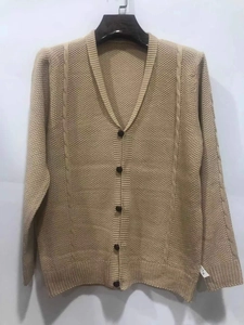 Macro detail of beige cable knit cardigan fabric with vintage brown buttons and ribbed hem