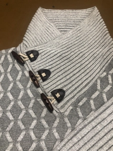 Detail of grey knit sweater showing shawl collar with faux leather horn buttons buckle