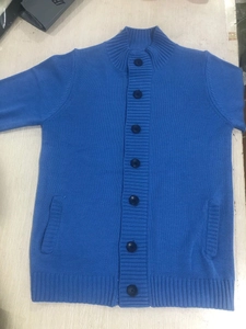 Detail of blue men's knit cardigan featuring ribbed cuffs and seven dark blue buttons