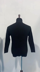 Close-up of black cable-knit sweater detail showing thick texture and high collar