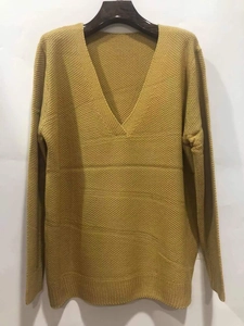 Detailed macro view of ginger yellow V-neck knitted sweater with waffle texture and ribbed cuffs