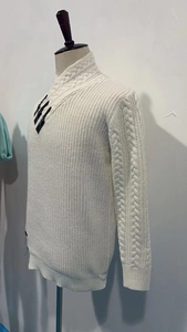 Detail of cable knit pattern and leather buckle on beige men's turtleneck sweater